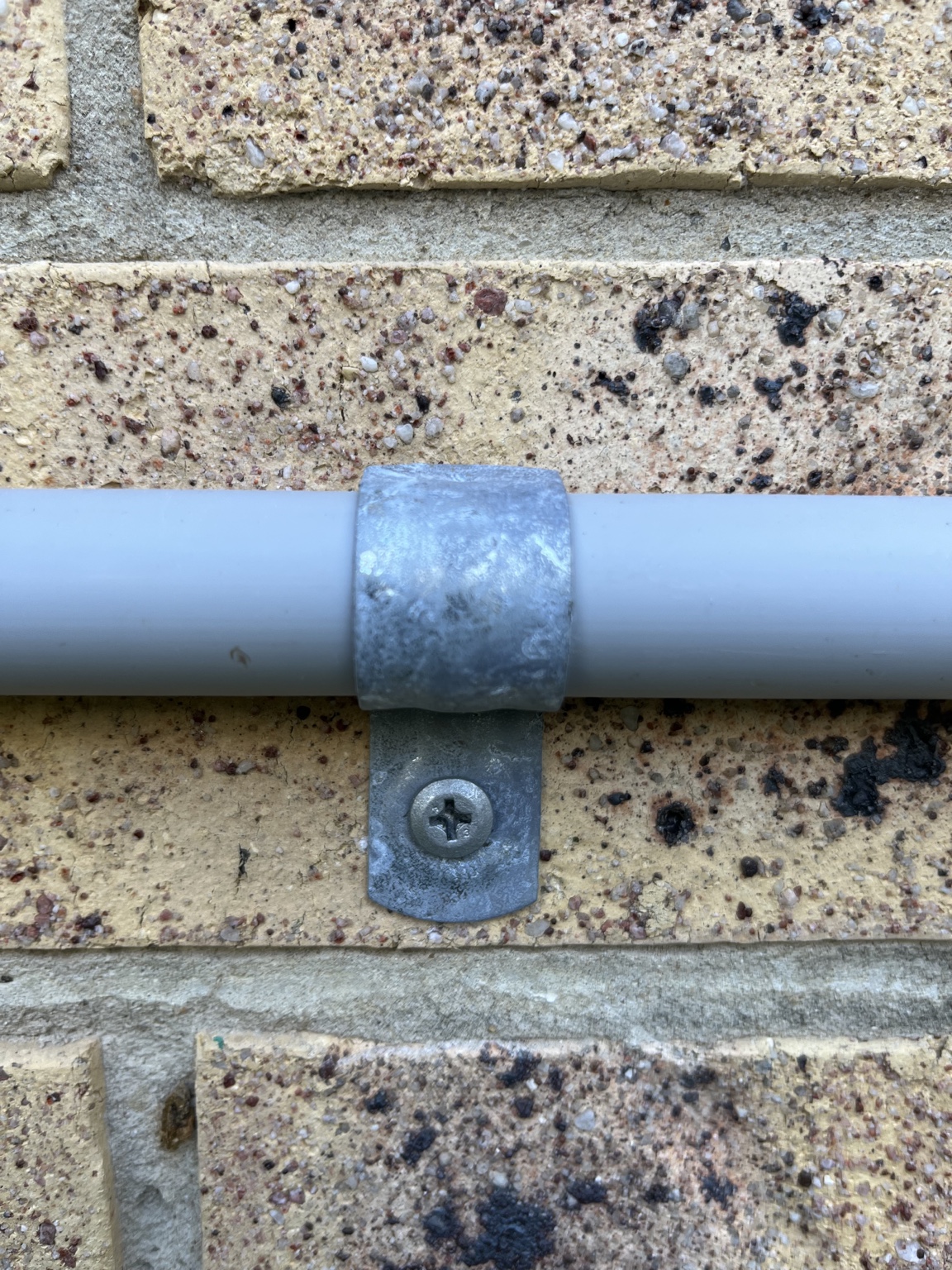 Galvanised saddle and screw securing air conditioning pipework