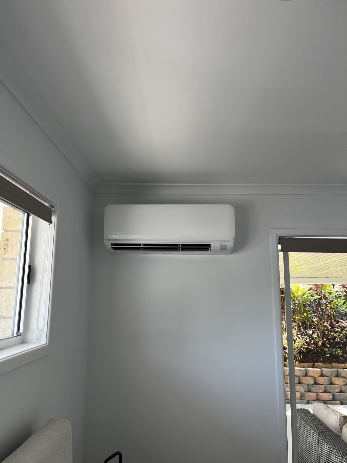 Split-system indoor unit positioned between a window and sliding door