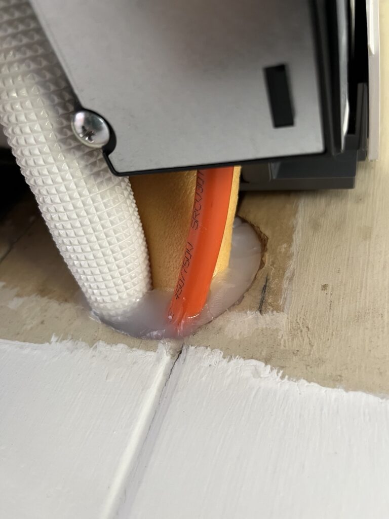 Sealed wall opening around air conditioning pipework, behind the indoor unit